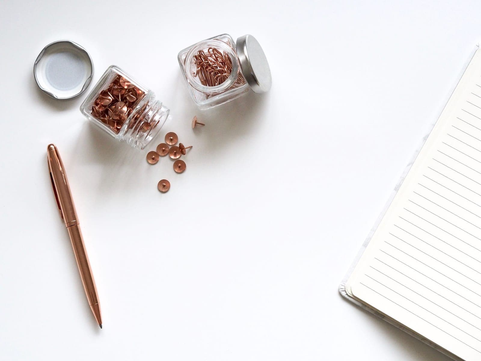 A notebook and a glass jar on a desk in daylight