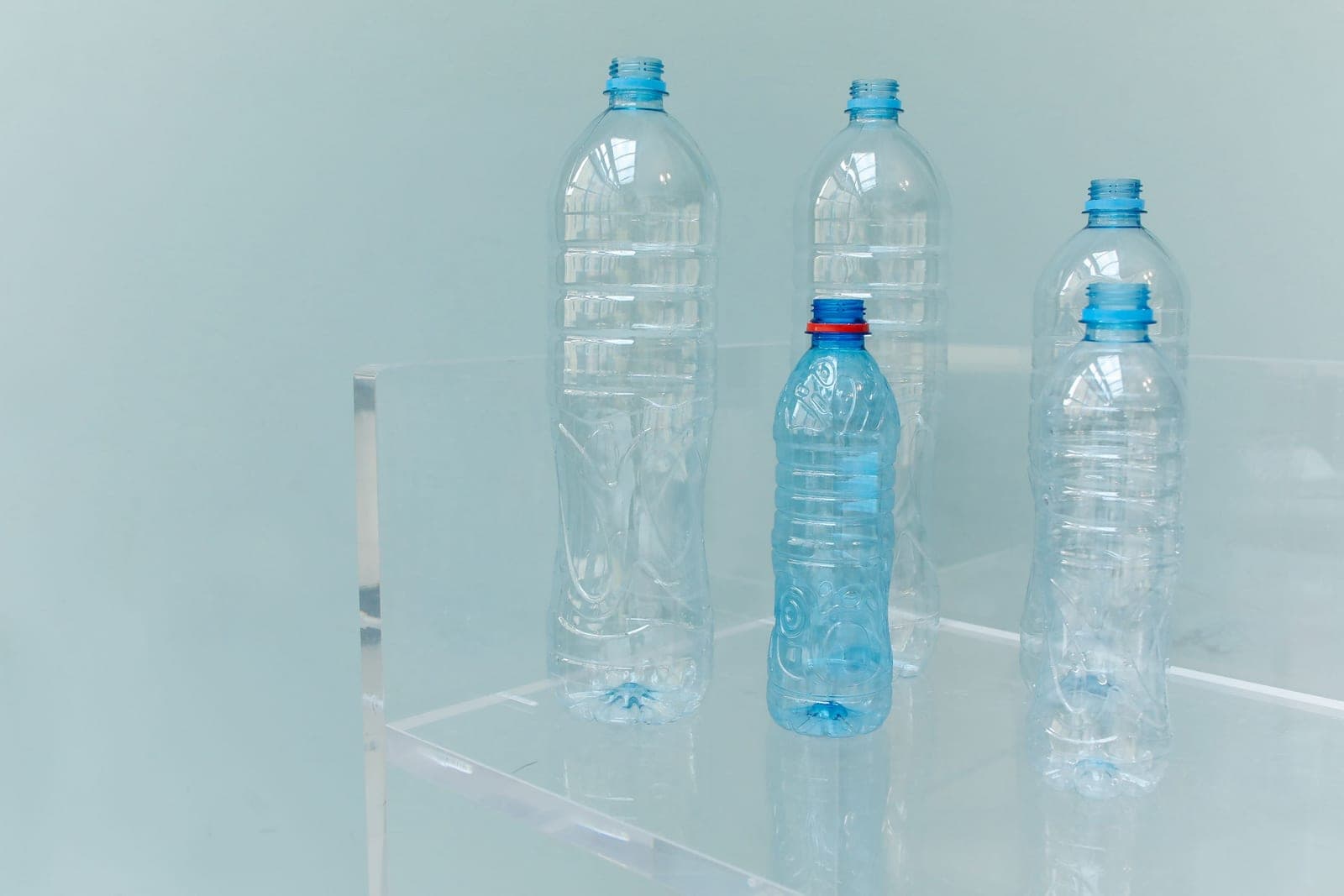 A plastic bottle and a glass bottle side by side on a white background