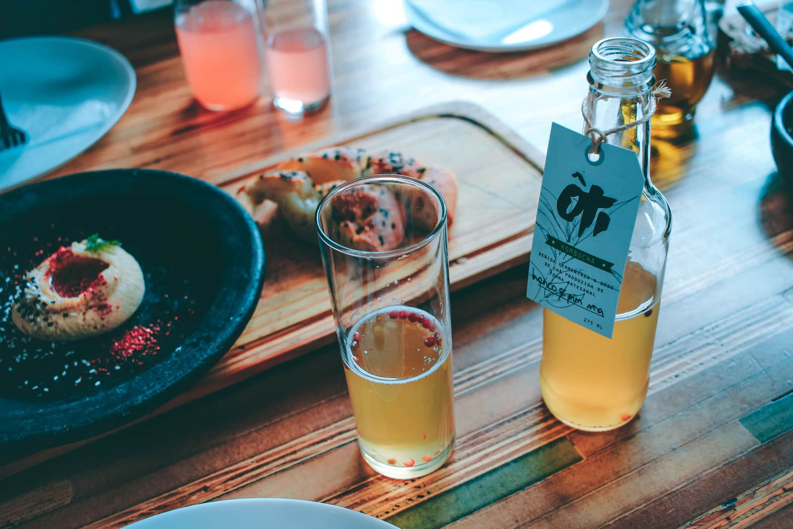 A glass of kombucha standing on a table in daylight