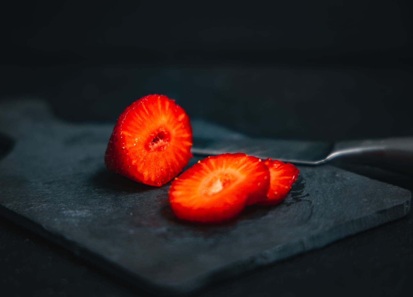 Sliced fruit and berries on a white board in bright light
