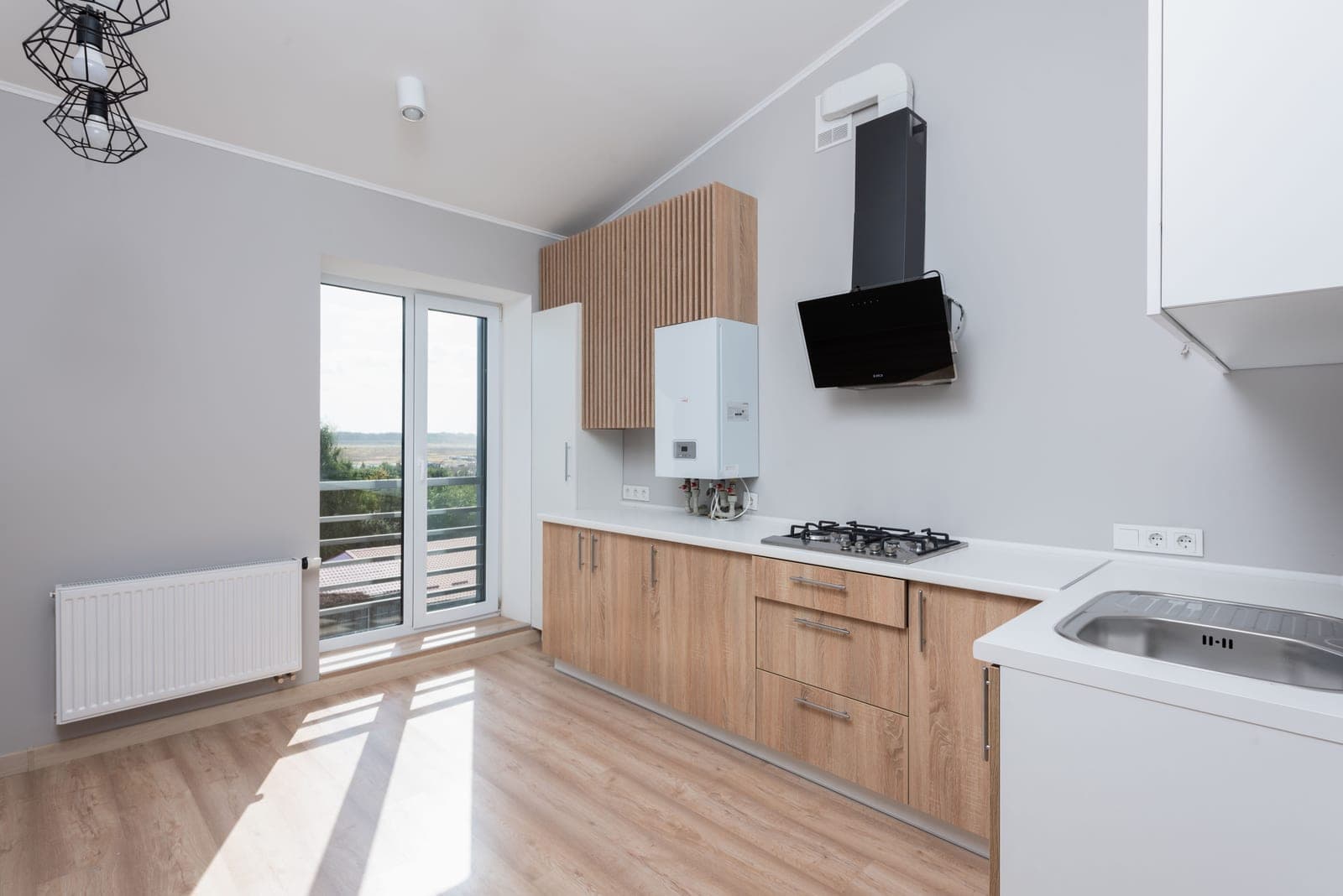 An empty kitchen with wooden cabinets and daylight through a glass door