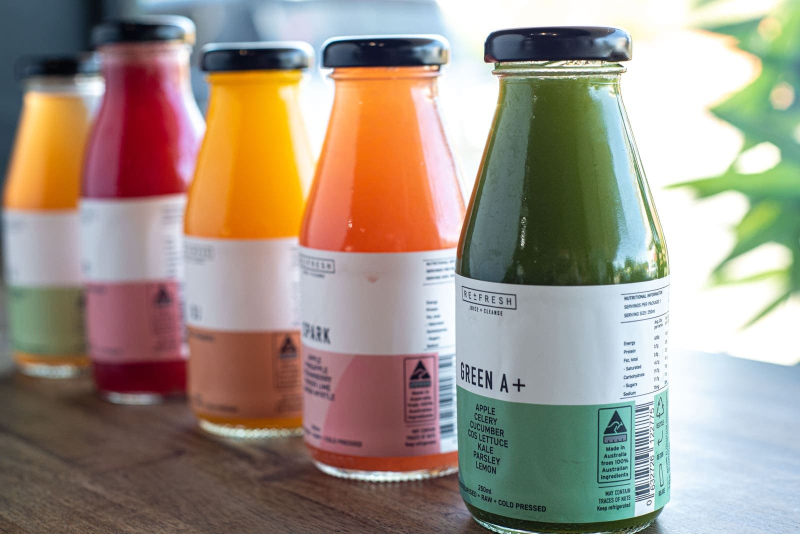 Assorted bottled fruit drinks in clear glass bottles on a wooden table