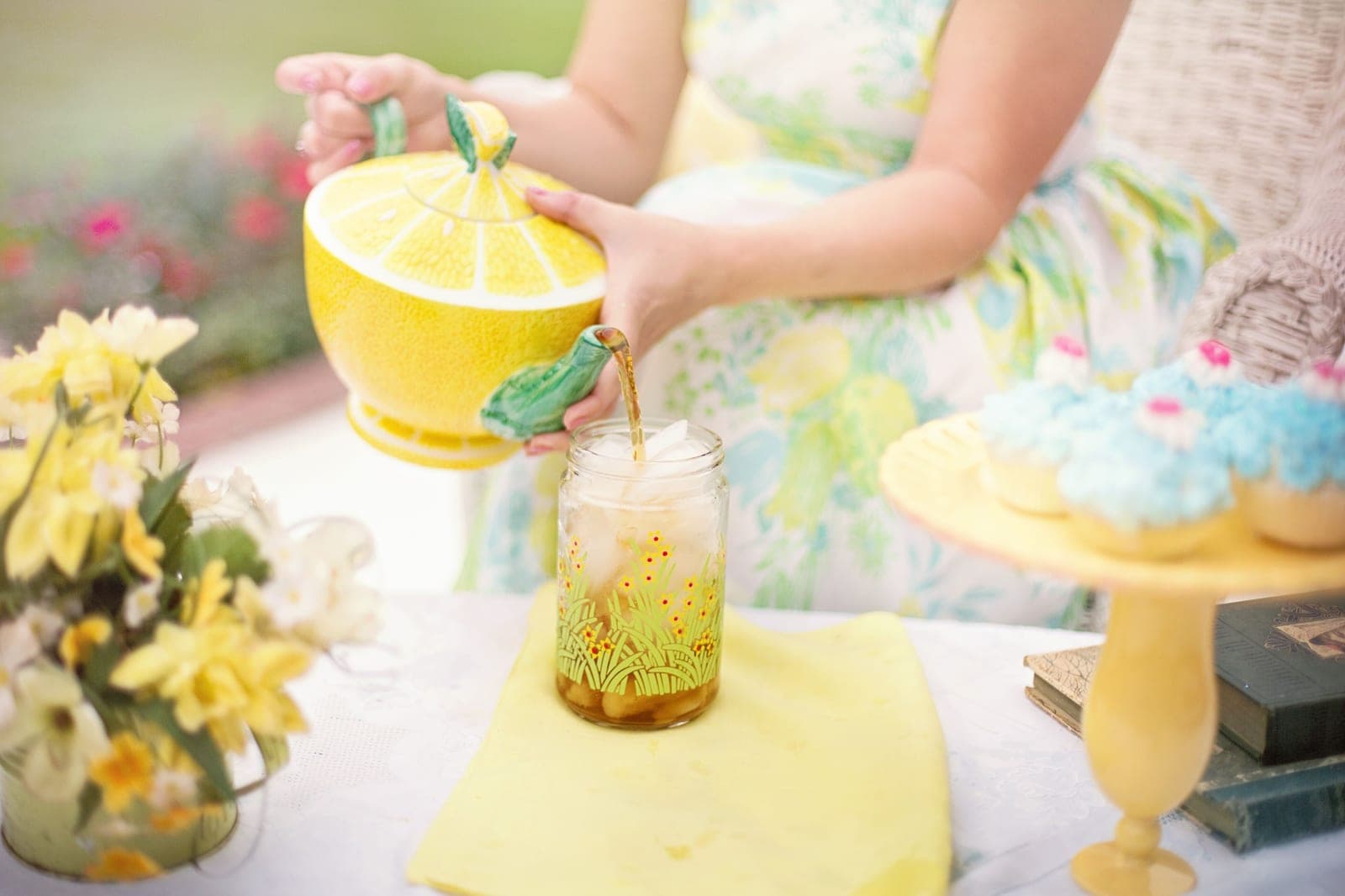 Tea being poured into a large glass jar in a bright kitchen