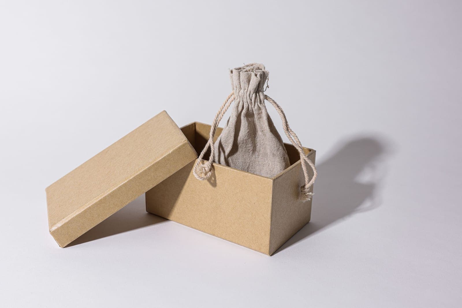 A plain gift box with natural linen on a bright minimal surface