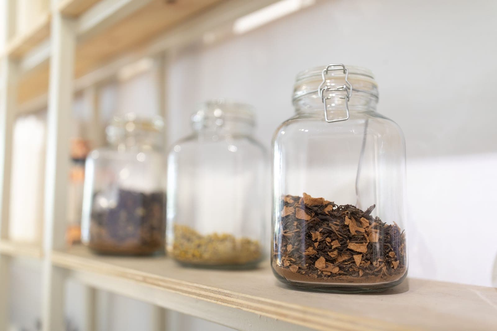 Empty glass jars standing on a white kitchen shelf in daylight